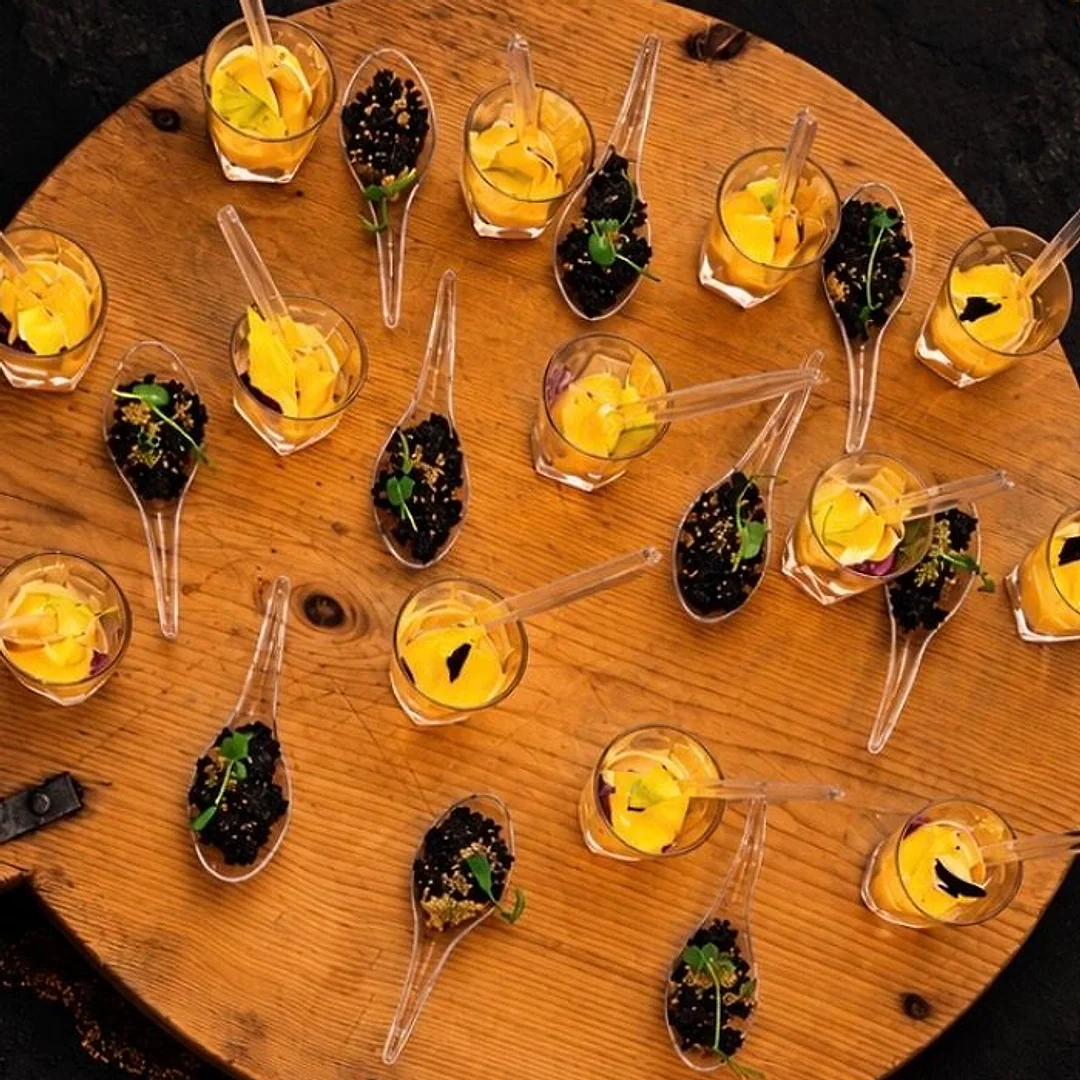 Verrines et cuillères d’amuse-bouches vues de près, sur une planche en bois